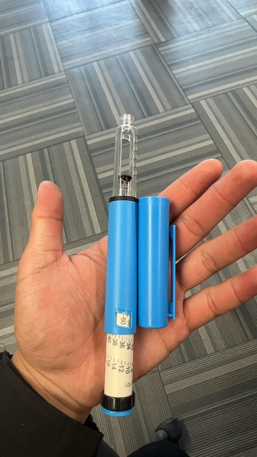 Blue reusable pen injector sample held for scale