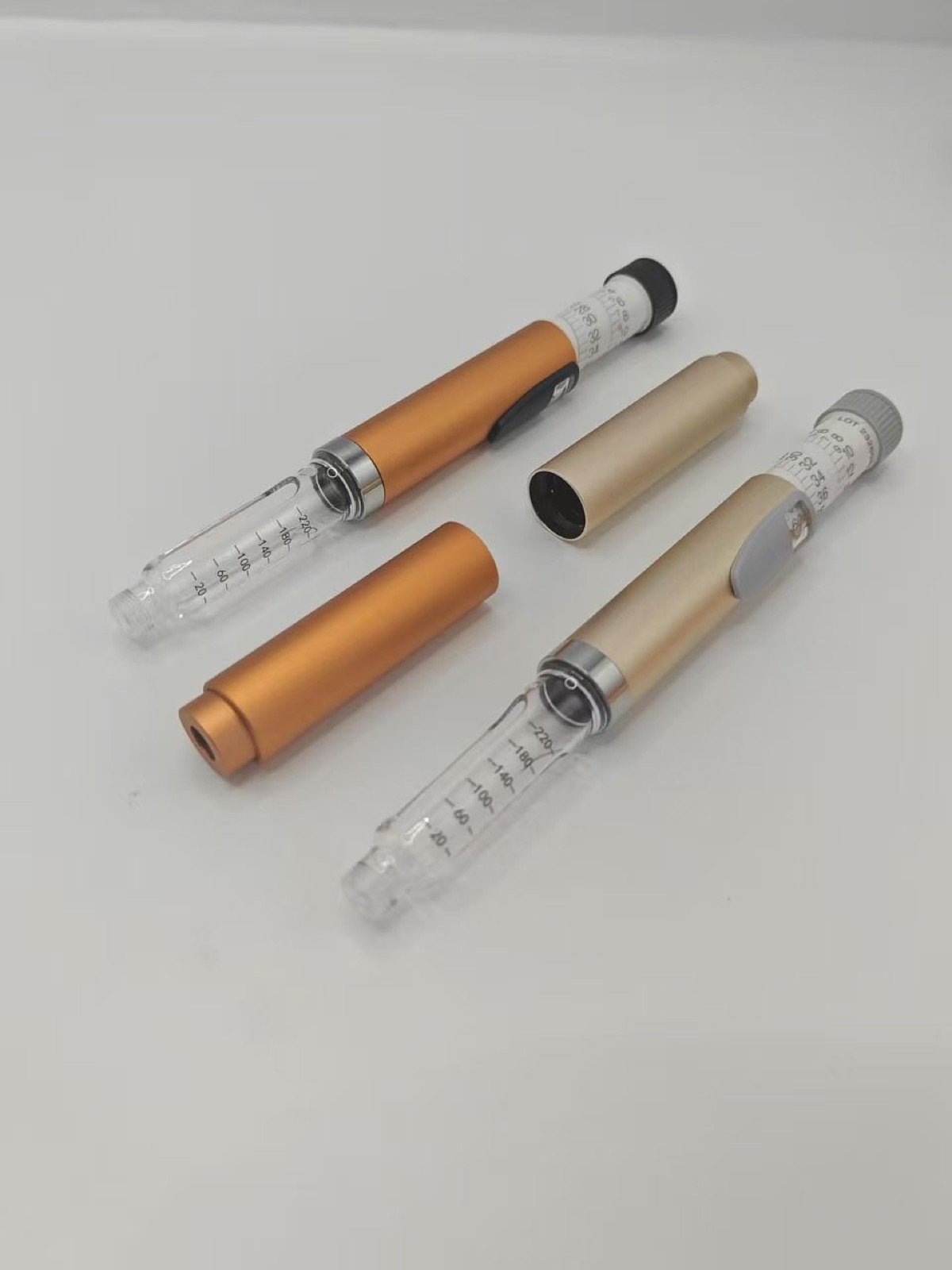 Gold and orange reusable pen injector samples opened for review