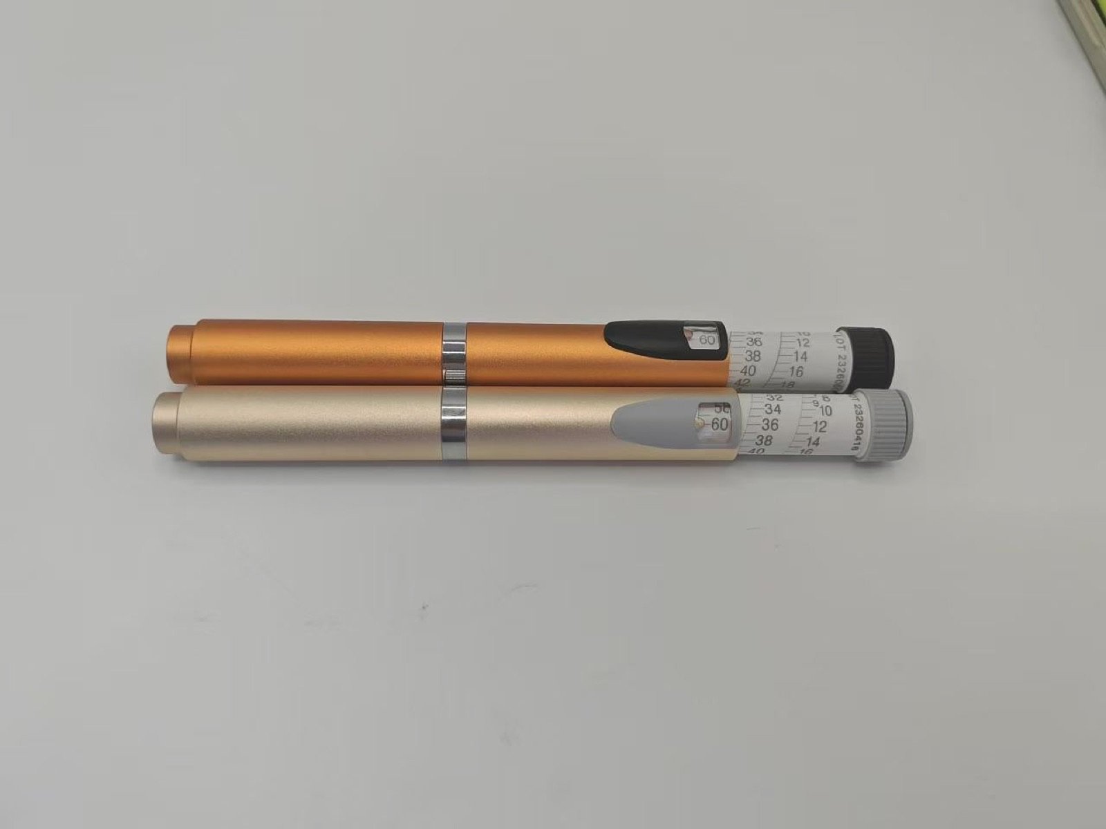 Two warm metallic pen injector samples